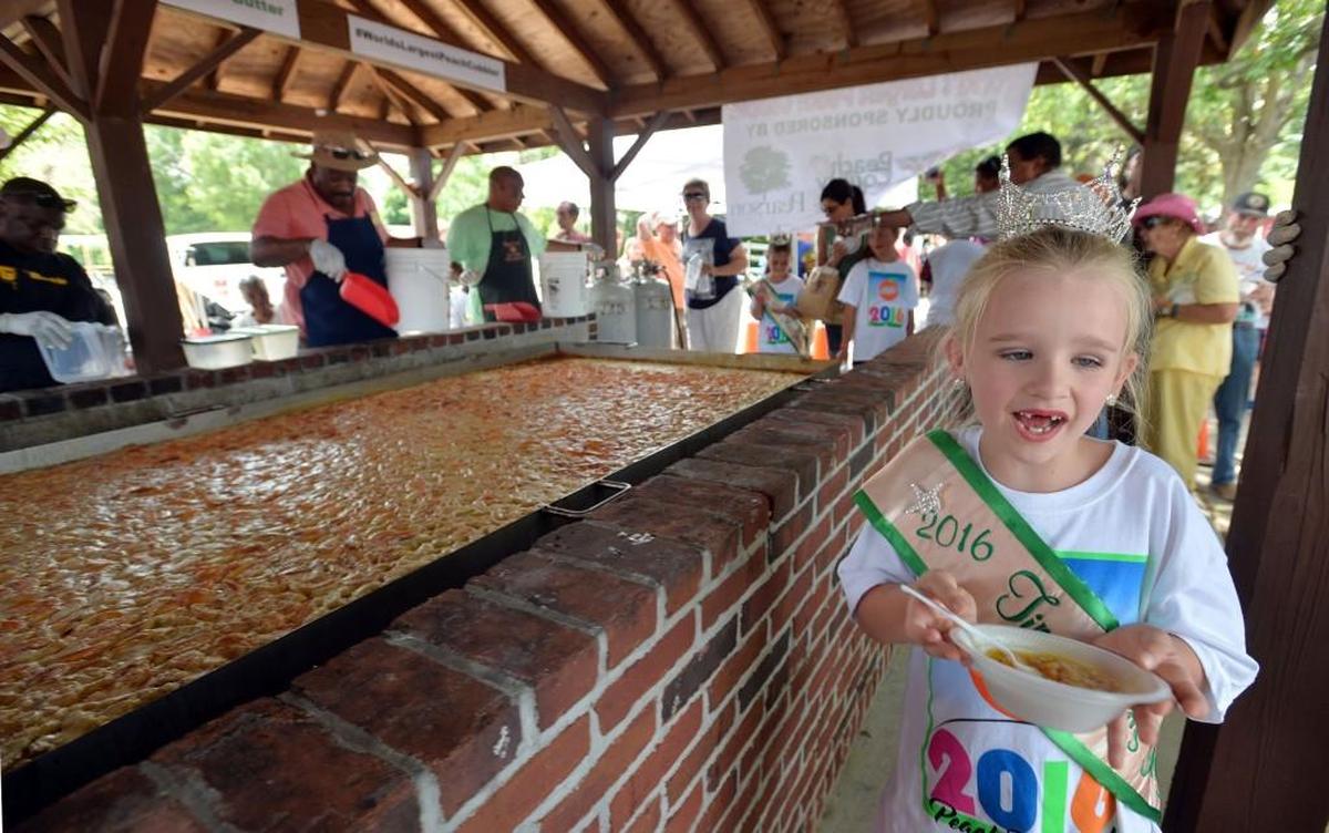 Bella Grace Sanders of Forsyth, the 2016 Tiny Miss Georgia Peach, gets a sample of the 800-pound peach cobbler at last year’s Peach Festival in Fort Valley.