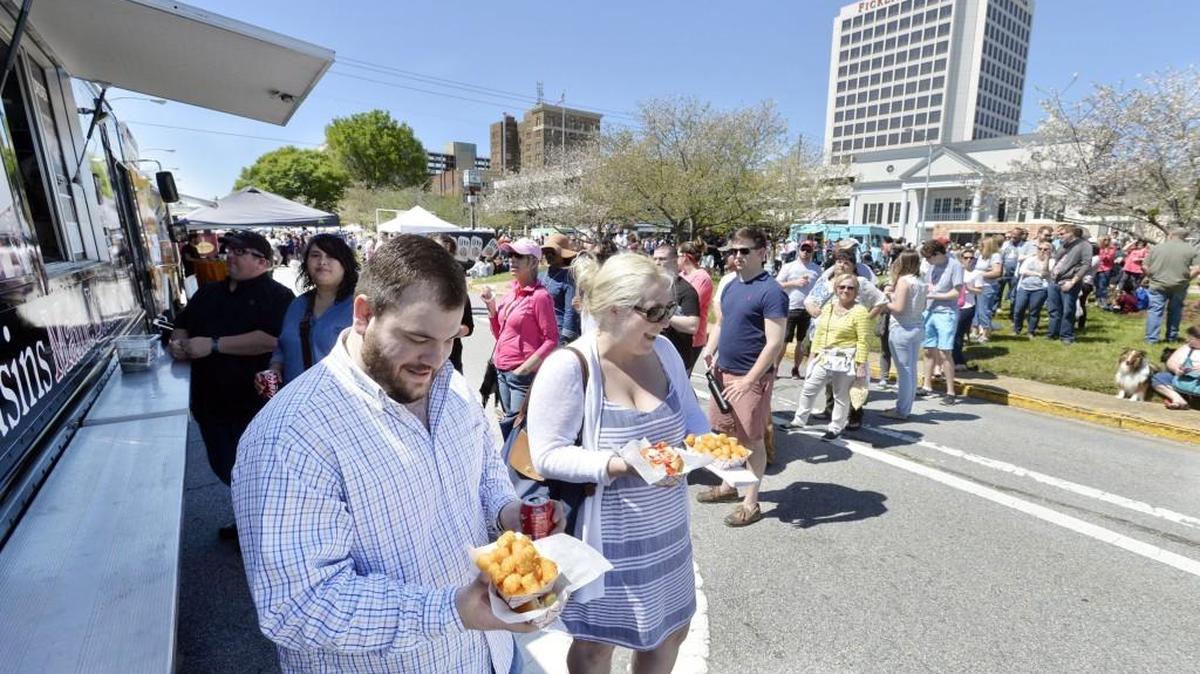 Dustin Cromer and Alexandria Snider, both with lobster rolls, look for a place to picnic with their lunch after standing in a block-long line waiting for what was a very popular food truck at the Mulberry Street Arts and Crafts Festival last year.