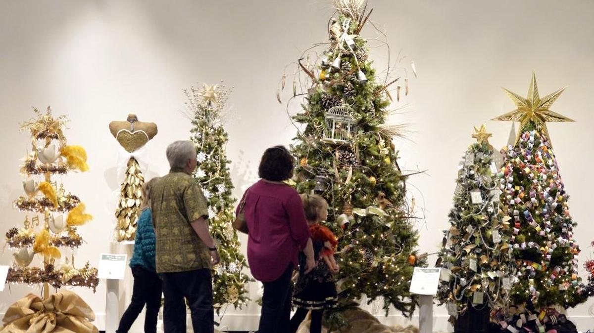Julie McAfee looks at Christmas trees on display at the Museum of Arts and Sciences with her daughters Zoe, left, and Malin and cousin Jay Larrin during the “Festival of Trees” exhibit. The exhibit is on display through Jan. 15.