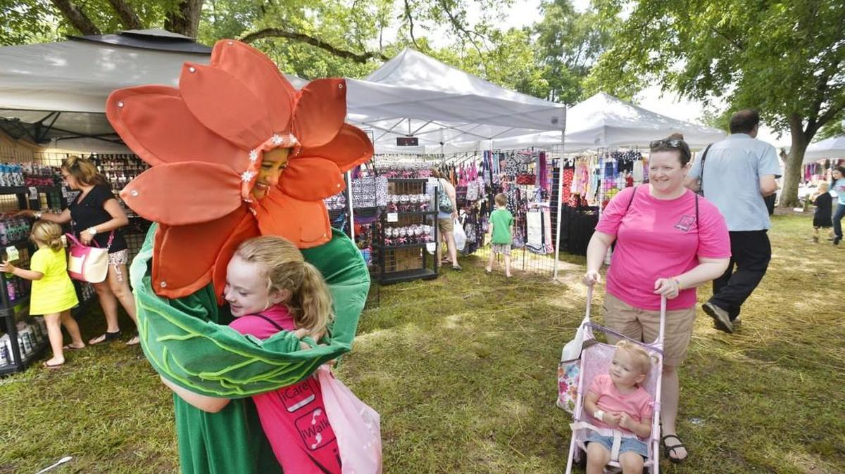 “Lily,” portrayed by Madison Thompson, gives Bethany Altman a hug at the 2014 Daylily Festival, as her mother, Kerri, and younger sister Bailey look on.