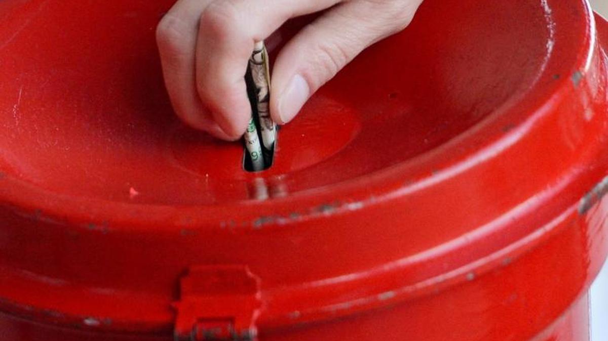 A donor places money in a Salvation Army red kettle.