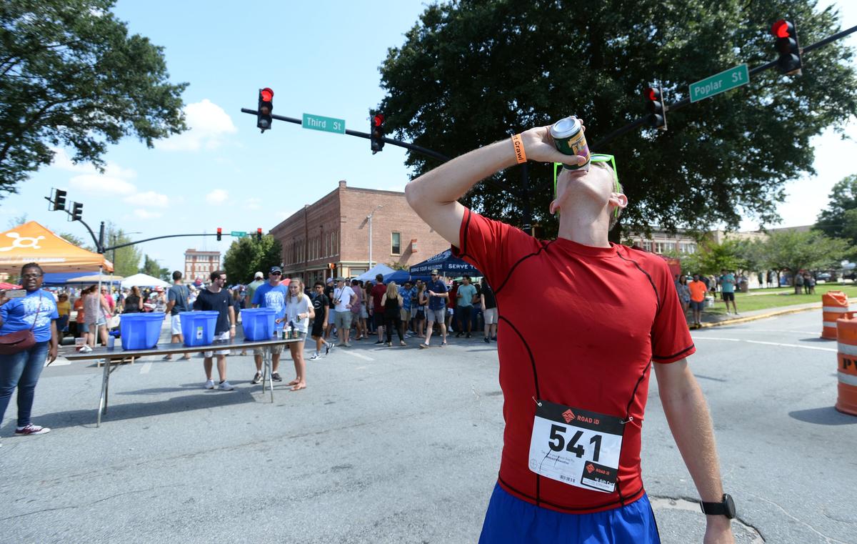 Macon Beer Festival goers watch Bryan Danely knock back a Tybee Island Blonde en route to a victory in the beer mile run Saturday. Before the start of each quarter mile, contestants had to drink a 12-ounce brew. Danely said lots of training was the key to his win as most of the 2,000 attendees sopped up suds from about 50 brewers along shady spots on Poplar Street.