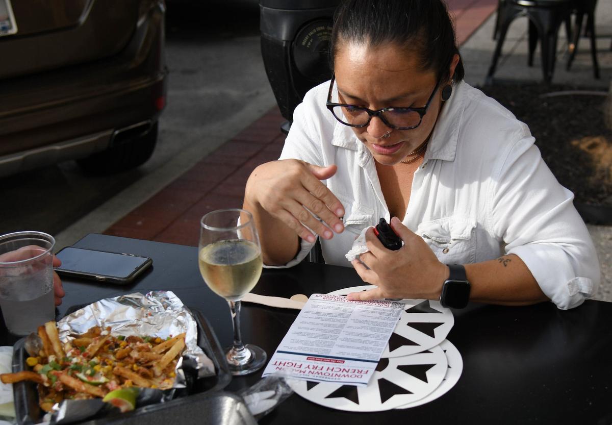 RJ Marcelona reads the Newtown Macon guide to the 3rd annual Downtown Macon French Fry Fight on Wednesday, July 10, 2024, outside of Ocmulgee Brewpub in downtown Macon, Georgia. Twenty downtown Macon restaurants participated in the competition, where each participating restaurant created a unique french fry special for the day in competition with other local restaurants.