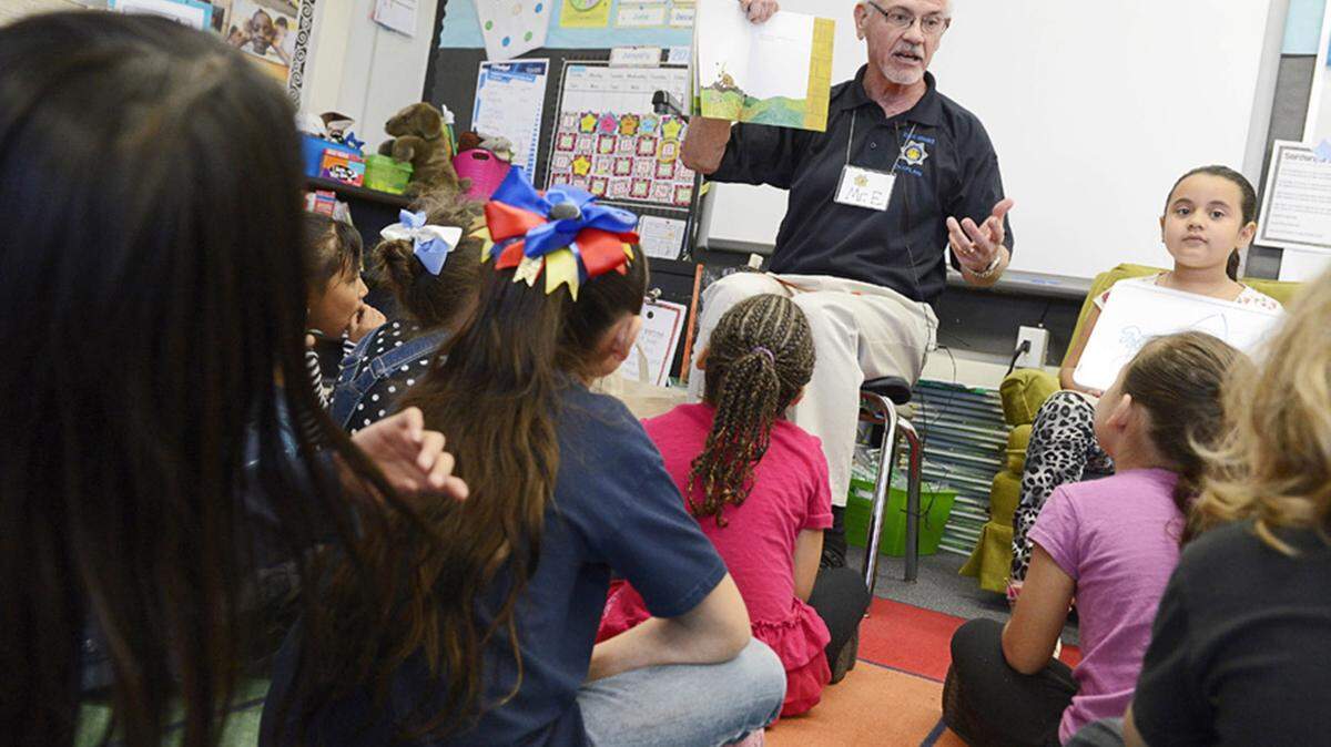 CRAIG KOHLRUSS/FRESNO BEEJohn Edmondson, with the Fresno Police Chaplaincy, reads to Julie Haqmmack's first grade class at Pyle Elementary School on Jan. 15 in Fresno, California.