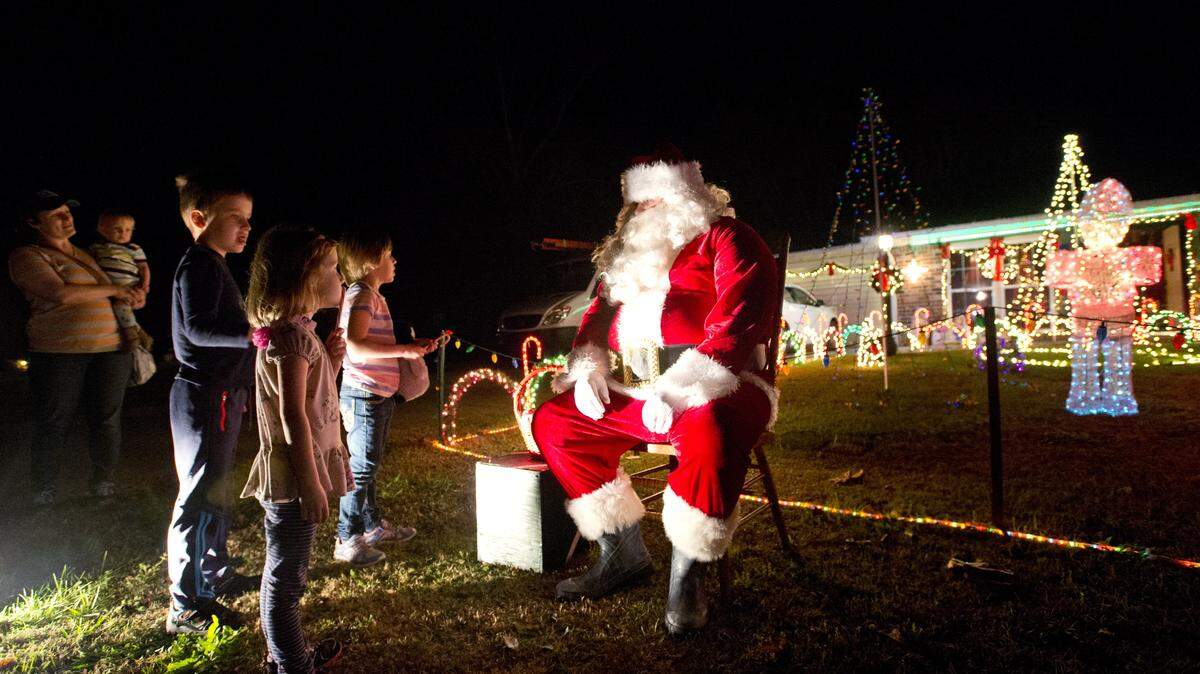 Santa Claus speaks with young members of the Nash family at the Christmas lights display at the Floyds' home.