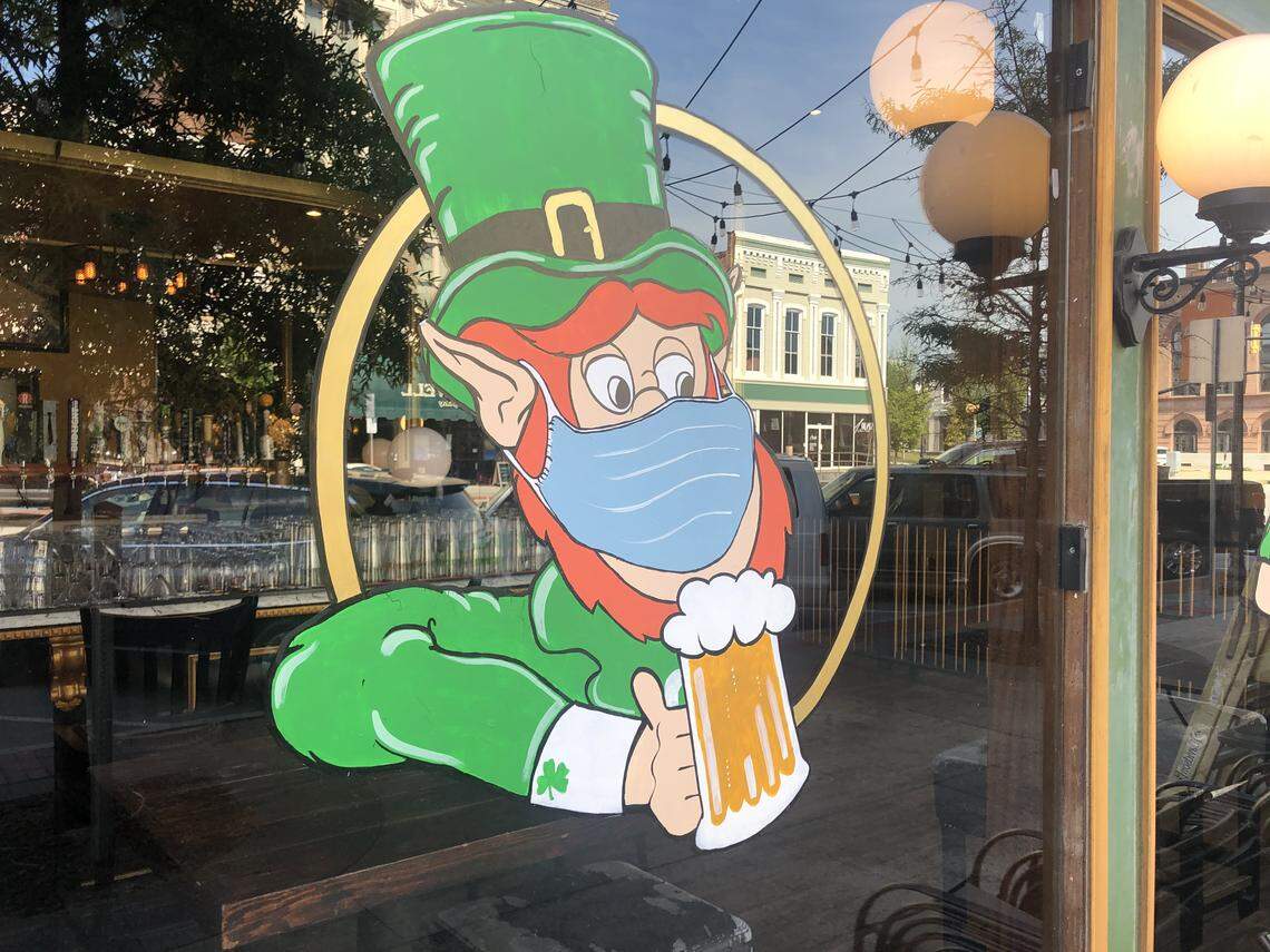A painting on the front window of the Bearfoot Tavern on Second Street in downtown Macon depicts a surgical mask-wearing leprechaun.