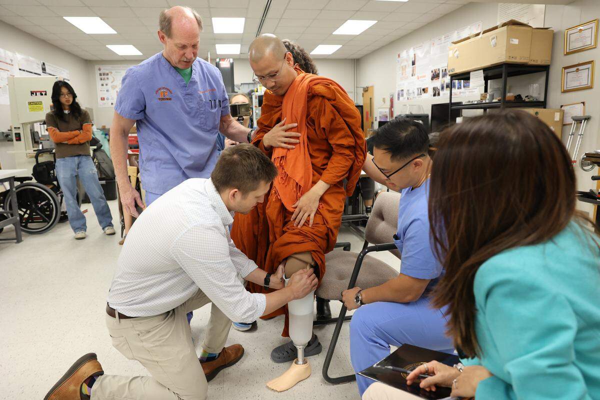 Doctors from the Mercer On Mission team fit Buddhist monk Bhante Dam Phommasan for a new prosthetic leg after he was injured in an accident during the national Walk for Peace.