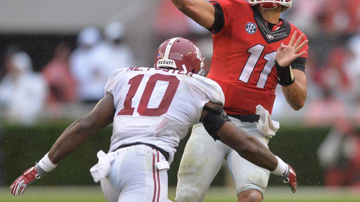 Georgia quarterback Greyson Lambert cuts loose with his first pass of the game under pressure from Alabama’s Rueben Foster.