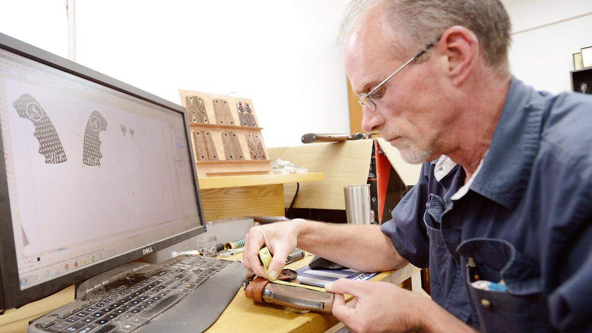 Matt Clough, owner of DSP Laser, measures the grip of a Colt Python 357 in his shop off Hawkinsville Road.