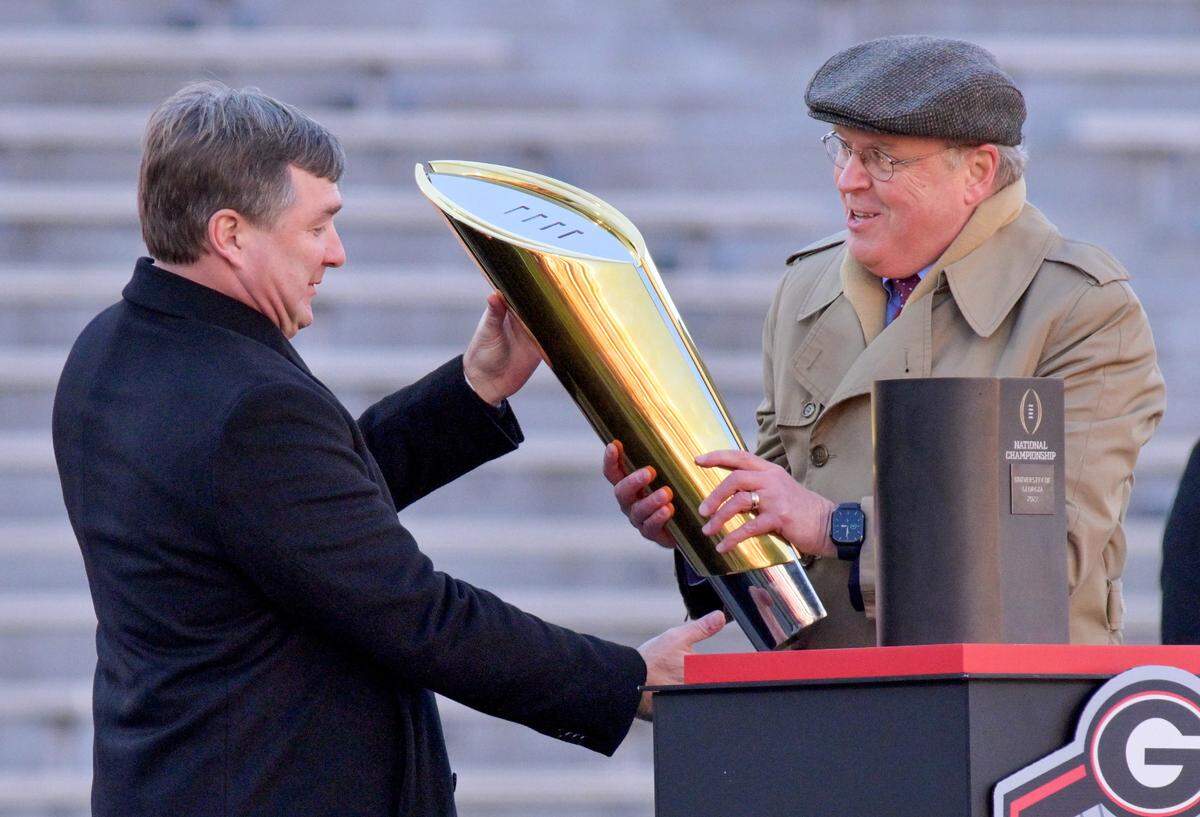 Georgia head coach Kirby Smart accepts the National Championship Trophy from Bill Hancock, executive director of the College Football Playoff during Saturday’s celebration in Athens.