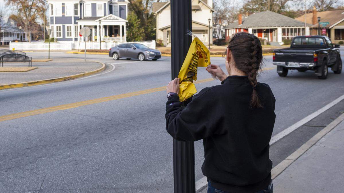 ​Josie Mazurkiewicz, a Mercer University student working in the Mercer Police Department, takes down one of the last wanted posters in Mercer Village that offered a $10,000 reward for information leading to the arrest of the man who fired shots at students in the area on Jan. 10, 2018. Quentin James Sanders, 41, was charged in the shooting, as well as several other violent crimes, including three homicides.