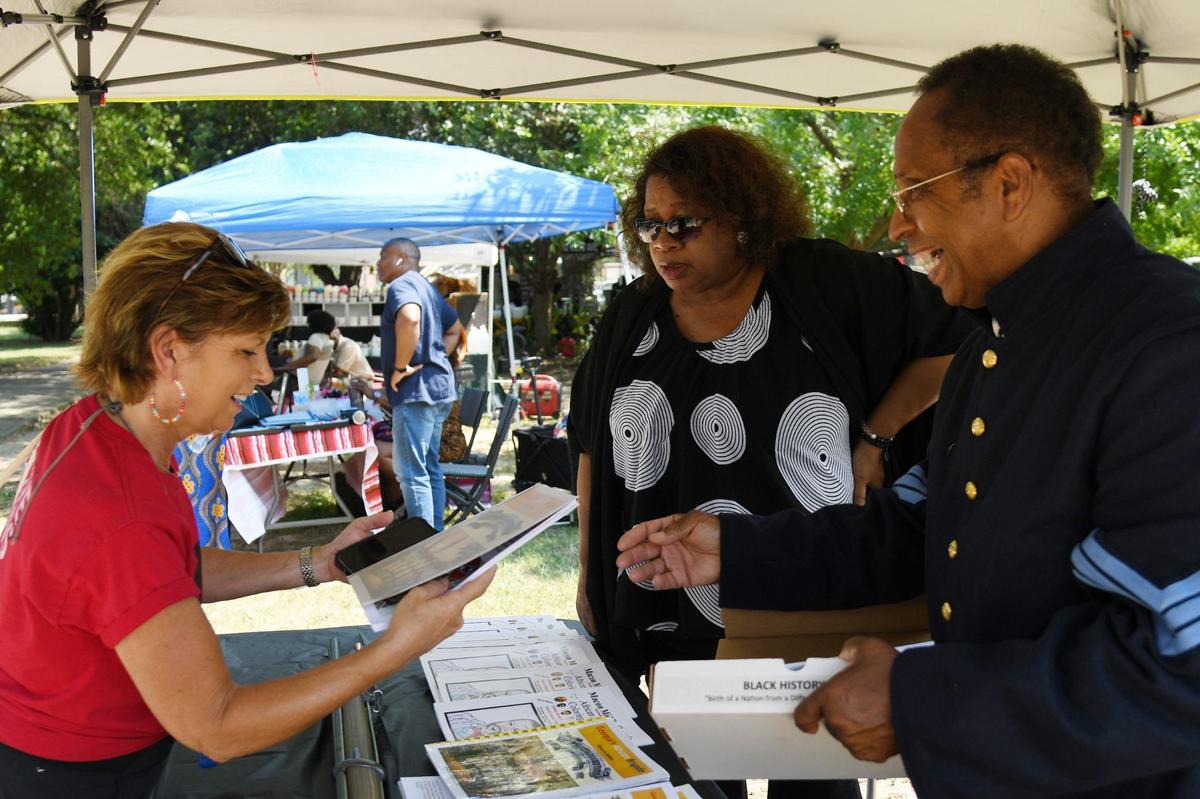 Lonnie Davis (right) shares a copy of his informational booklet “Georgia African Brigade: Slave to Soldier” with an attendee next to his wife Theresa Harvey-Davis (middle) during the 32nd Juneteenth Freedom Festival on Saturday, June 15, 2024, at Tattnall Square Park in Macon, Georgia. Davis does living history presentation on the Georgia African Brigade, three Black Union regiments that organized in Macon during the Civil War.