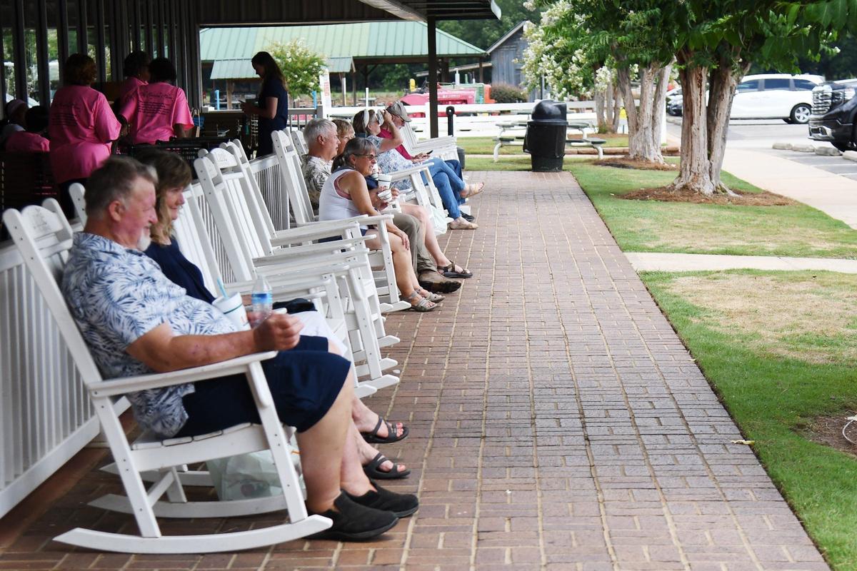 Visitors sit in rocking chairs outside of Lane Southern Orchards on Thursday, July 18, 2024, in Fort Valley, Georgia. Lane Southern Orchards serves 300,000 visitors a year with peaches as the roadside stop’s main attraction.