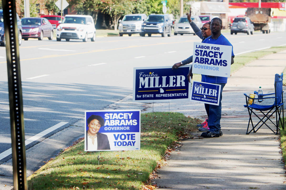 James Ashley and Cynthia Mosley campaign outside the Warner Robins Recreation Department precinct on Tuesday. Ashley said he has  campaigned at the location before and this was the busiest he had seen it.