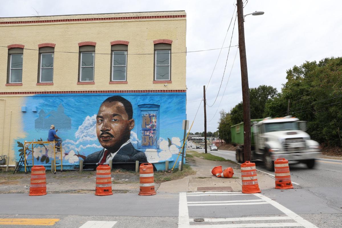 Cars drive by as Kevin “Scene” Lewis works on a mural of Rev. Martin Luther King Jr. on Wednesday, Sept. 11, 2024, off of Martin Luther King Jr. Boulevard in Macon, Georgia. The mural will depict King as well as cherry blossoms and Zion Baptist Church, the last place King visited in Macon before his assassination in 1968.