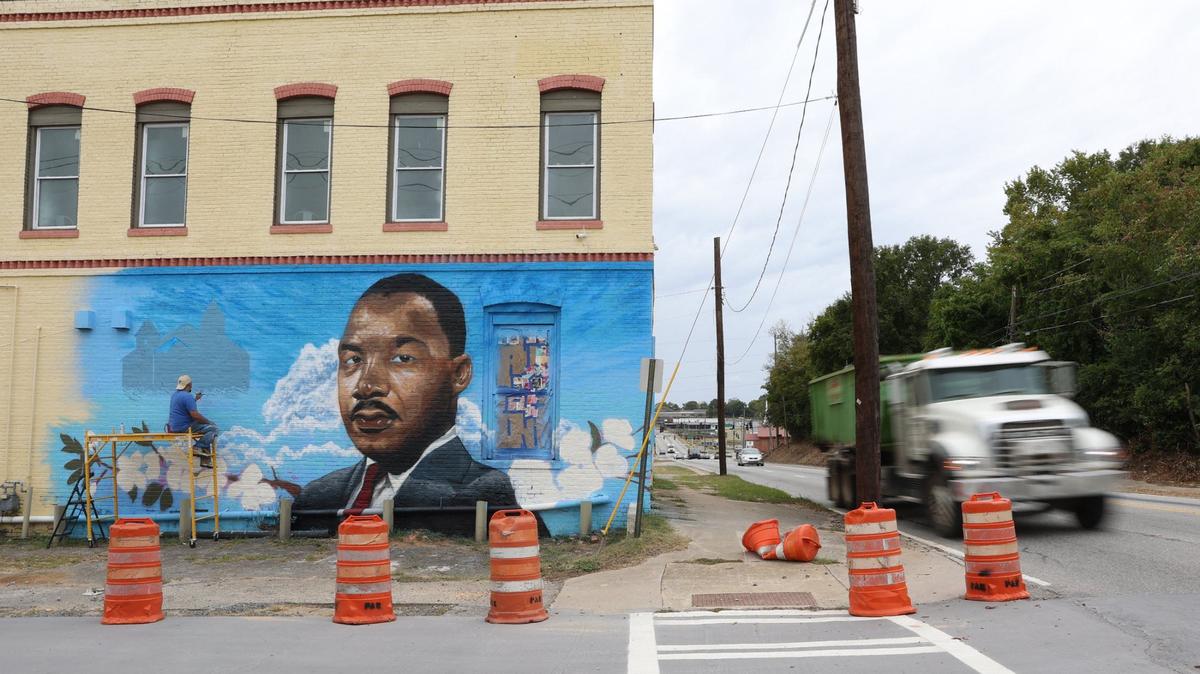 Cars drive by as Kevin “Scene” Lewis works on a mural of Martin Luther King Jr. on Wednesday, Sept. 11, 2024, off of Martin Luther King Jr. Boulevard in Macon, Georgia. The mural will depict King as well as cherry blossoms and Zion Baptist Church, the last place King visited in Macon before his assassination in 1968.