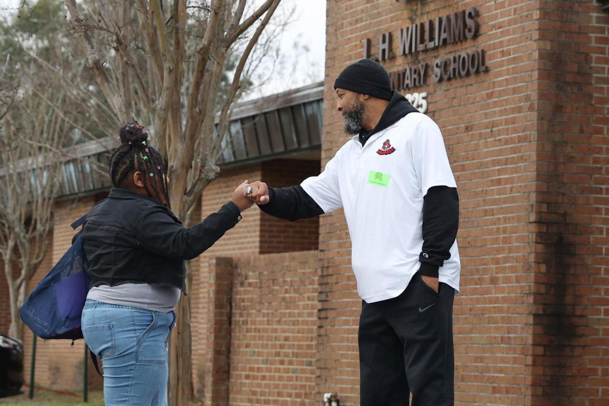 Macon Rampage coach Shayne Allen (left) fist bumps a student walking into L.H. Williams Elementary School on Thursday, Feb. 20, 2025, in Macon, Georgia. Members of the Macon Rampage, Macon’s semi-professional football team, welcomed students to school on the first day back from February break as a a part of the United Way’s Walking School Bus initiative to encourage student attendance.