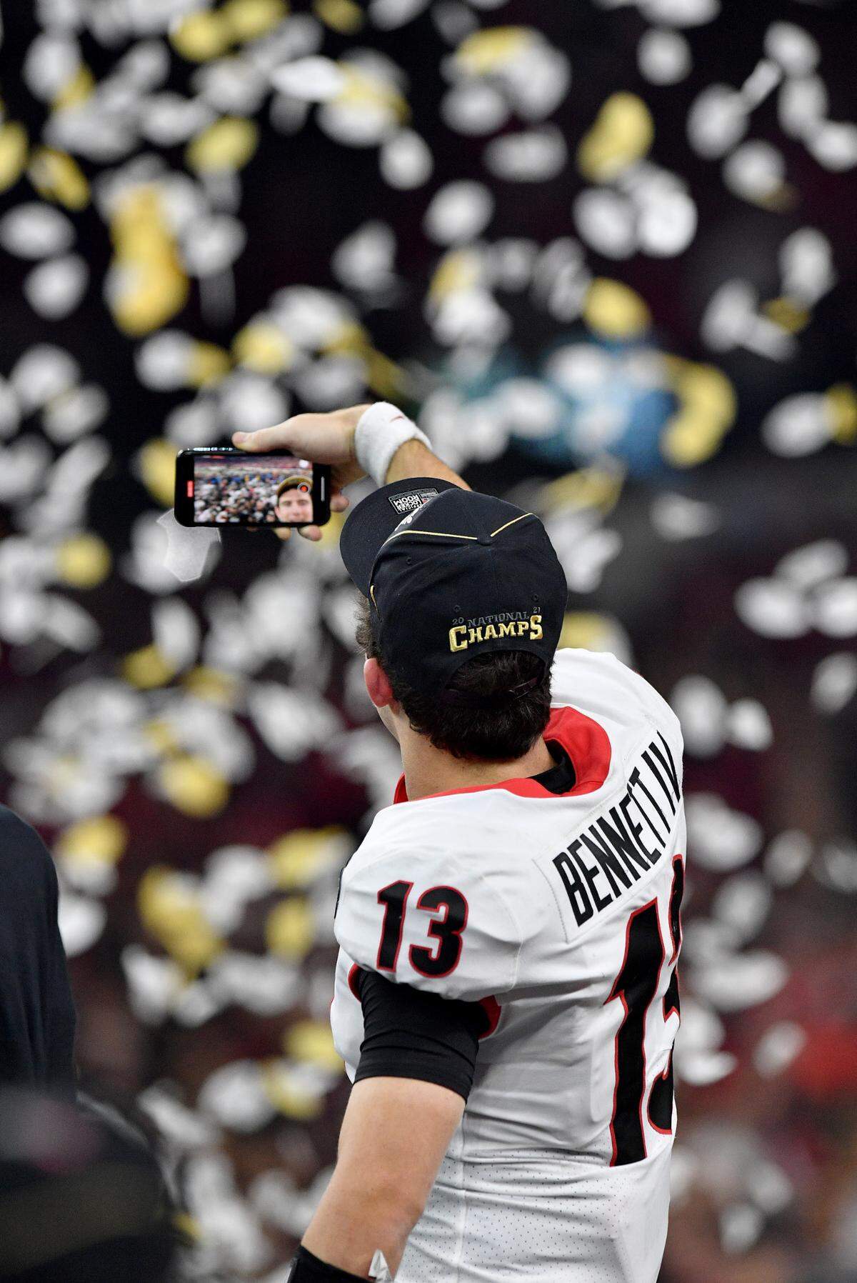 Georgia quarterback Stetson Bennett (13) holds up his phone after the Bulldogs’ 33-18 win over Alabama in the College Football Playoff National Championship game Monday night.