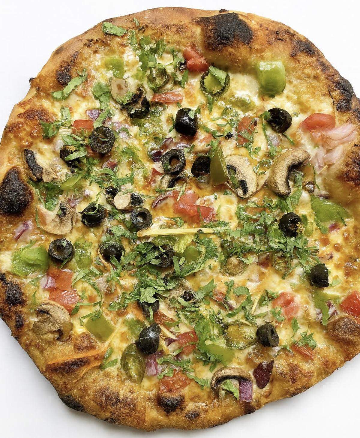 The “Desi Delight” veggie pizza at Slice & Spice includes red sauce, mozzarella, diced tomatoes, bell peppers, mushrooms, red onions, olives, jalapeños, ginger and fresh cilantro.