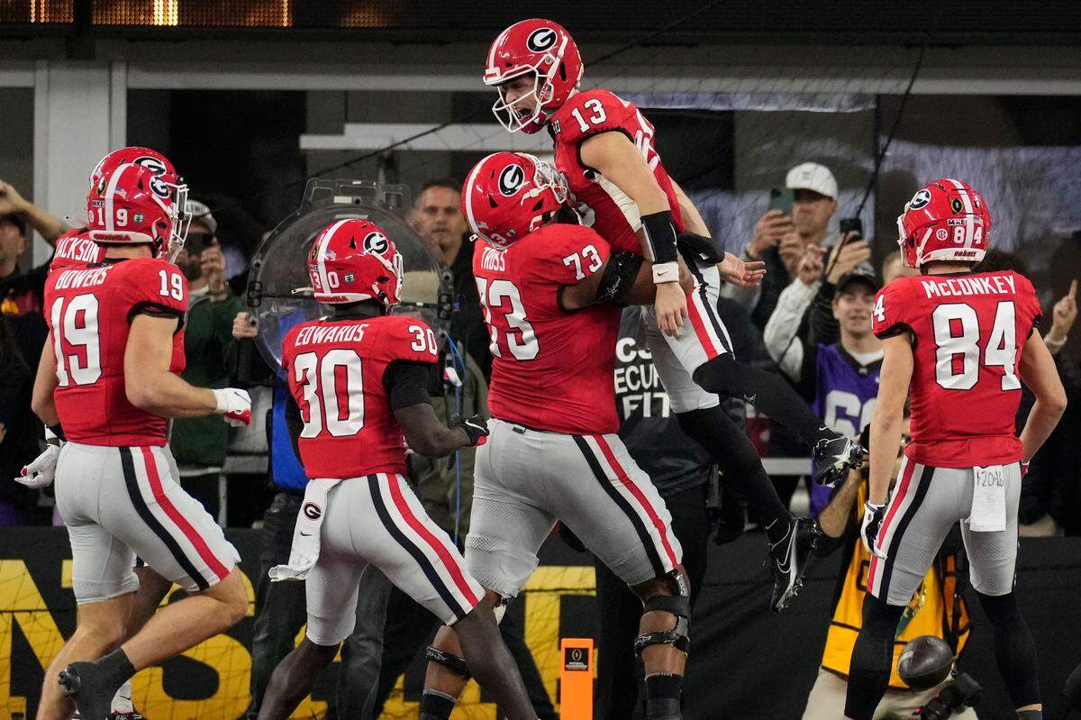 Georgia offensive lineman Xavier Truss (73) lifts Georgia quarterback Stetson Bennett (13) after Bennett scored a touchdown against TCU during the first half of the national championship NCAA College Football Playoff game, Monday, Jan. 9, 2023, in Inglewood, Calif. (AP Photo/Marcio Jose Sanchez)