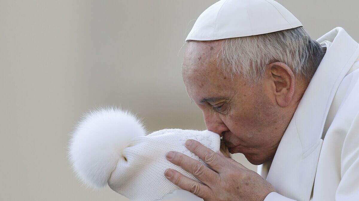 Pope Francis kisses a child upon his arrival for the weekly general audience at the Vatican, Wednesday, Dec. 16, 2015. Pope Francis enters his 80th year on Thursday amid mounting hopes among his critics that it will be his last _ at least as pope. (AP Photo/Gregorio Borgia)