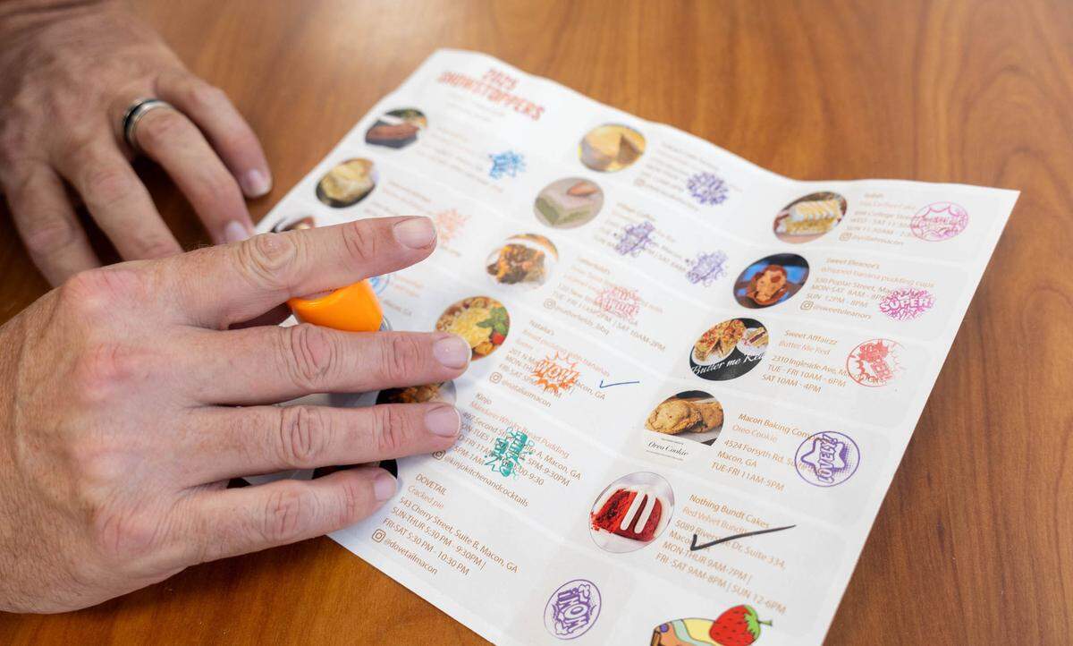 Steven Collins, co-owner of Layers bakery on Vineville, puts his very last stamp on his 2025 Macon Baking Week passport. He saved his bakeries stamp for last.