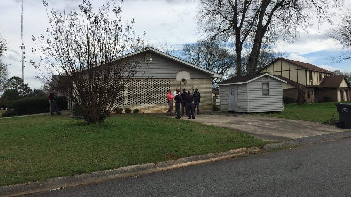 Forensic investigators gather Monday in the driveway outside of the house at Oakridge and Greenwood drives where Jerrell Walker, 19, was shot and killed during an alleged attempted robbery on Christmas night.