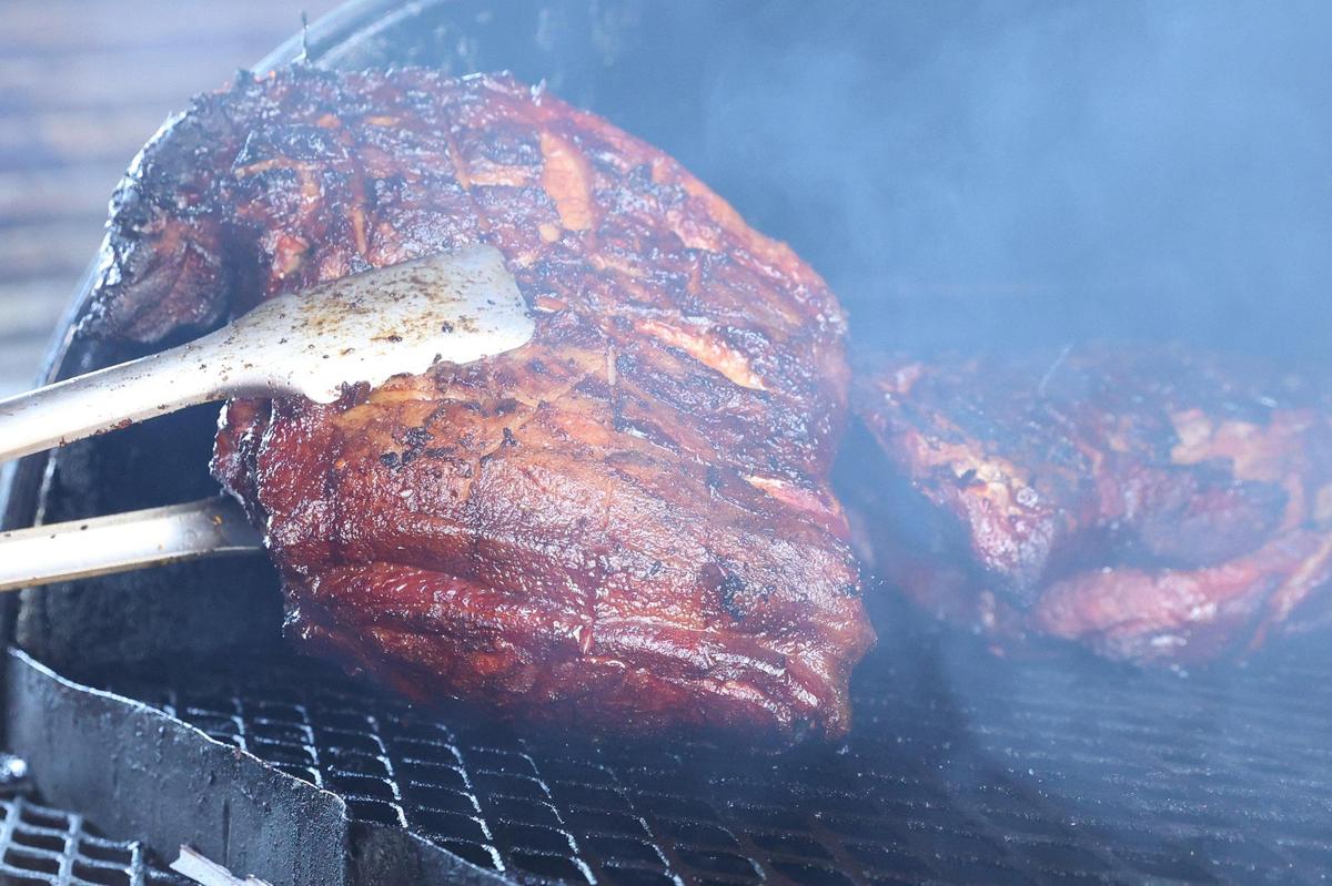 Q Time Barbeque owner Robert Parker flips two pork shoulders on the pit Thursday, March 20, 2025, at Q Time Barbeque in Warner Robins, Georgia. Parker said he begins cooking for the day early in the morning hours before opening and often sells out of items.