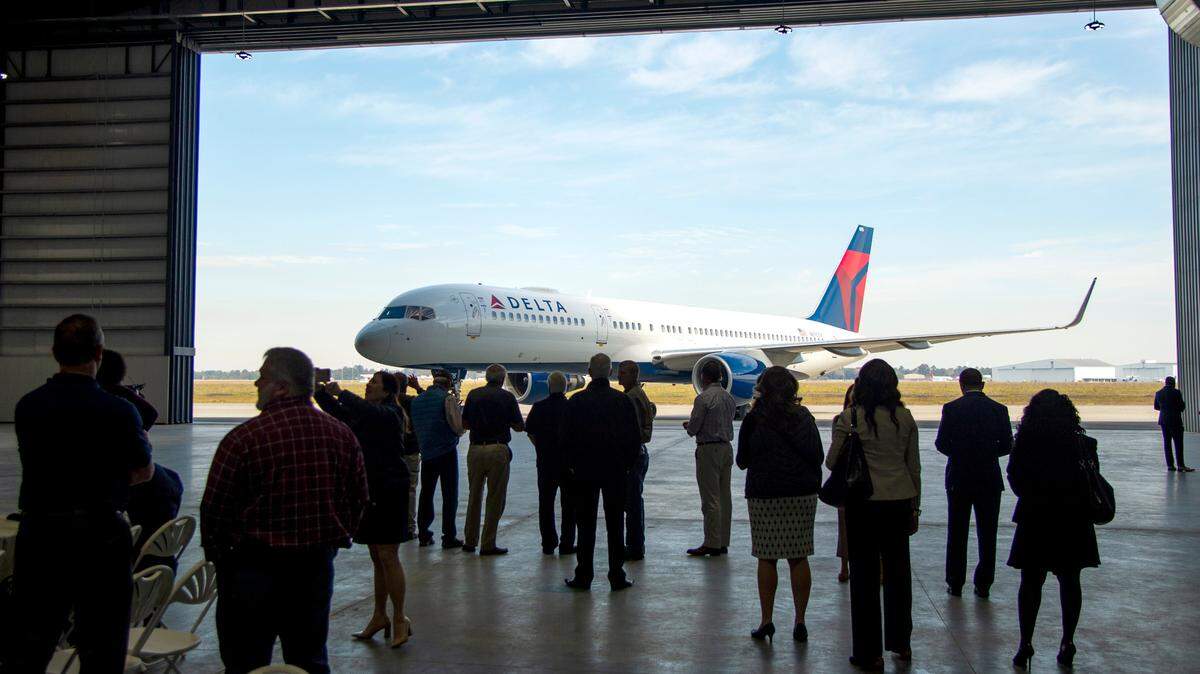 Guests turn to take a glance at a recently painted Delta Air Lines 757 during a grand opening ceremony of the Dean Baldwin Painting Wednesday morning at the Middle Georgia Regional Airport. The facility features four strip and paint hangers with 117,050 square feet of hanger floor space. 