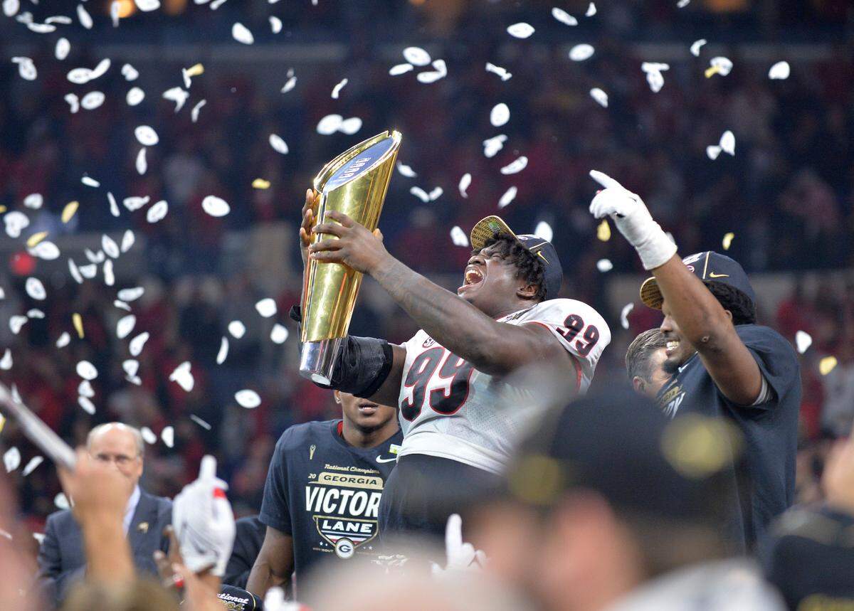 Georgia defensive lineman Jordan Davis (99) holds up the championship trophy after the Bulldogs’ 33-18 win over Alabama in the College Football Playoff National Championship game Monday night.