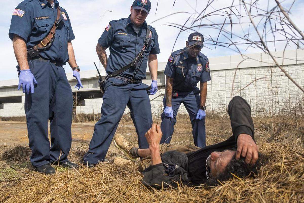 Firefighters leading a contingent of homeless census takers tend to an unsheltered man experiencing a medical issue by Interstate 16 in Macon. Firefighters and other first responders who frequently encounter homeless people informed the direction and geography of Macon’s 2024 census of the unsheltered.