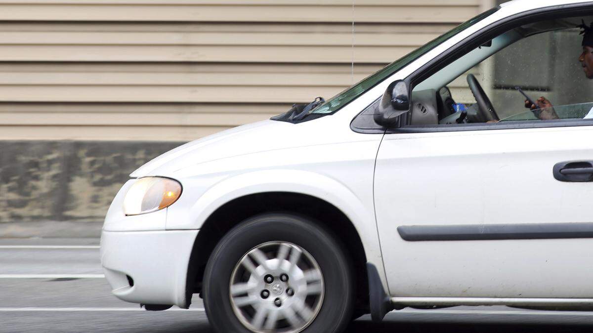 In this June 22 photo, a man looks at his phone on Interstate 70 in Atlanta. On July 1,Georgia is joined more than a dozen other states in banning hands-on cellphone use while driving.