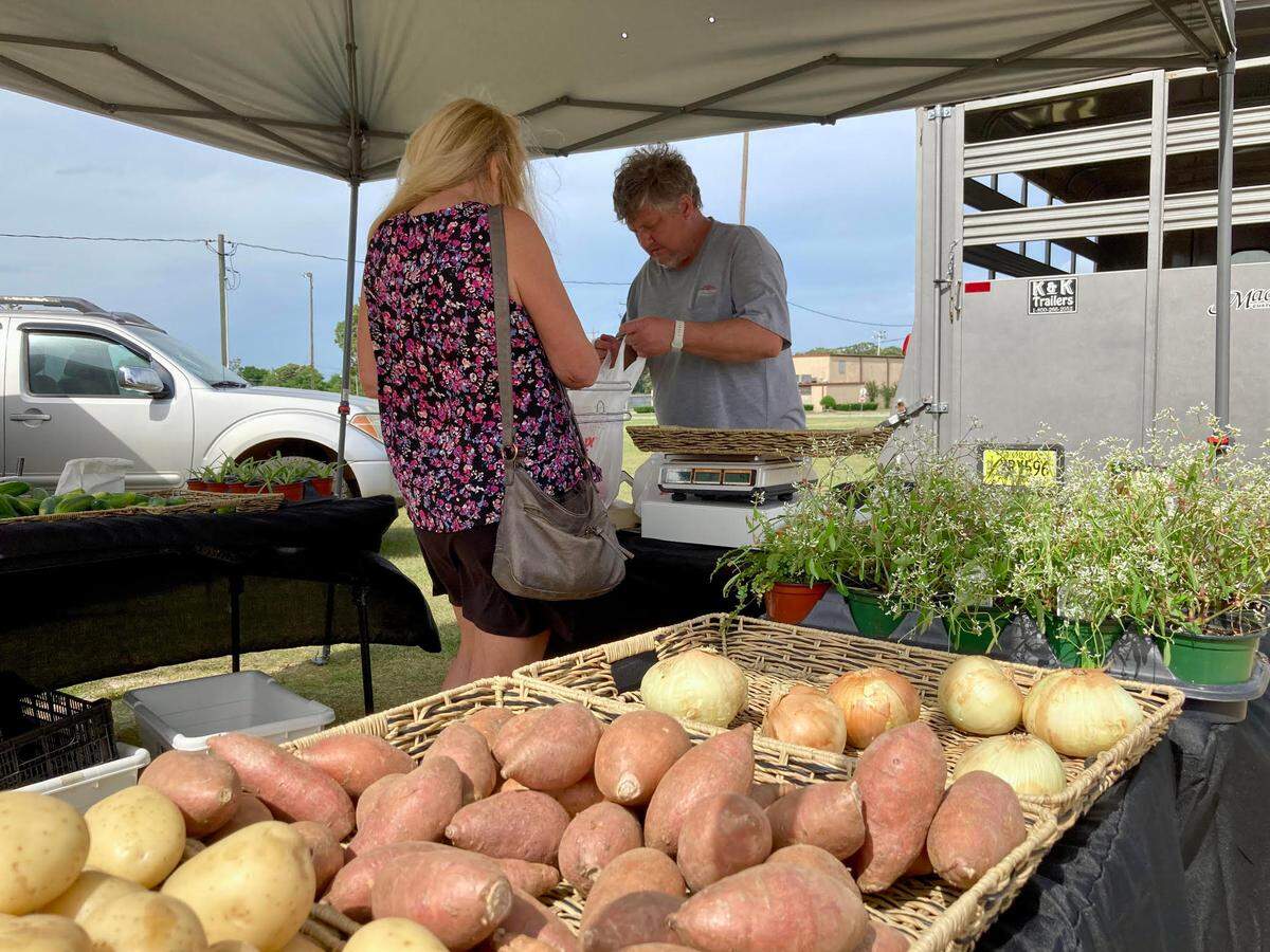 Greg Shiver, co-owner of The Riverbend Meadow Market in East Dublin, bags produce for a customer at the International City Farmers Market in Warner Robins. He and wife have a 20-acre farm in East Dublin. They make a living from farming, selling their produce at farmers markets across Middle Georgia.