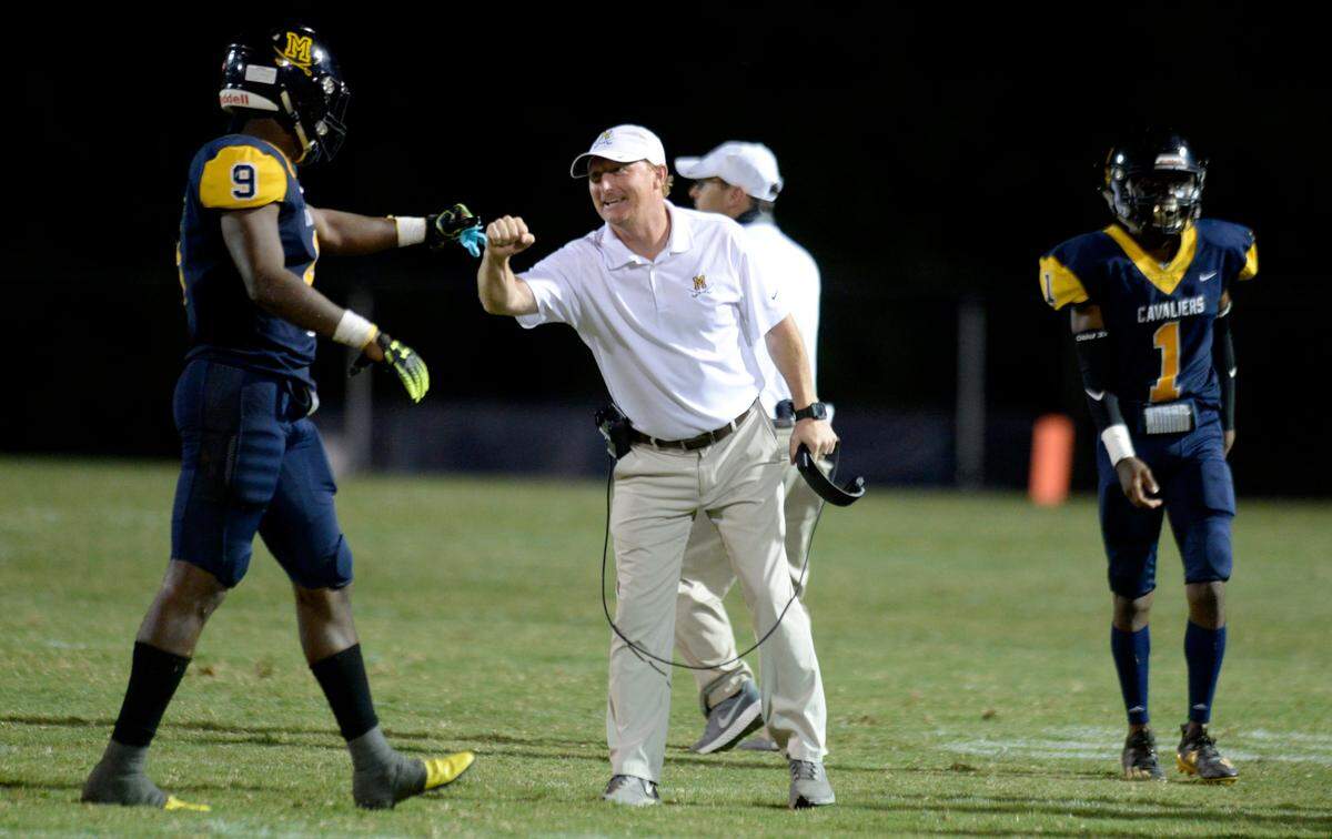 Former Mount de Sales head coach Keith Hatcher gives a fist bump to linebacker Fernando Washington. Hatcher is set to take over at ACE next season as their head football coach.