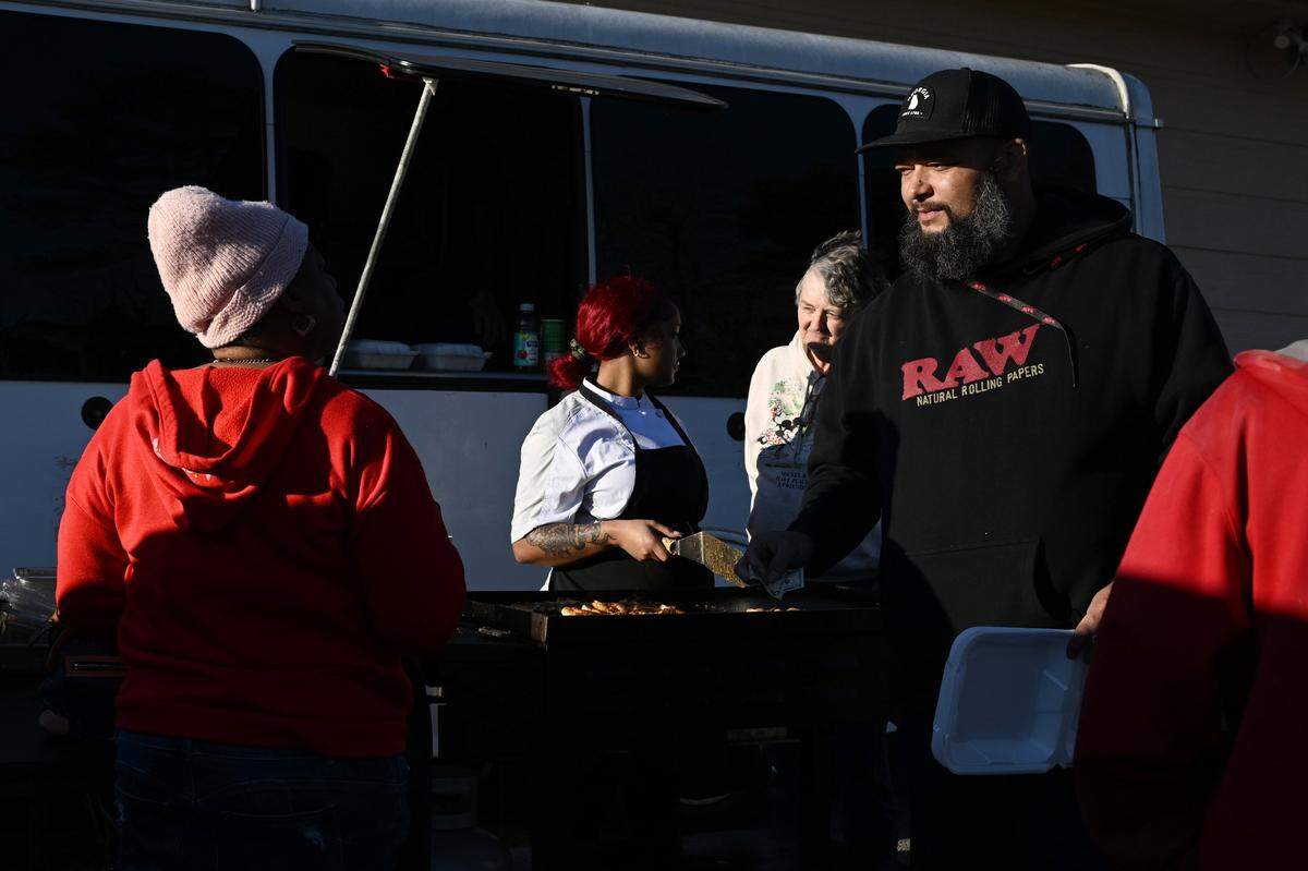 Phillip Hinson (right) takes a customer’s order while his daughter Jada Hinson, 21, speaks to her grandmother Diane Hinson on Friday, Feb. 6, 2026, in Shurlington Plaza in Macon, Georgia. Hinson sells loaded baked potatoes from a food truck in east Macon and is working to re-open a physical restaurant. 