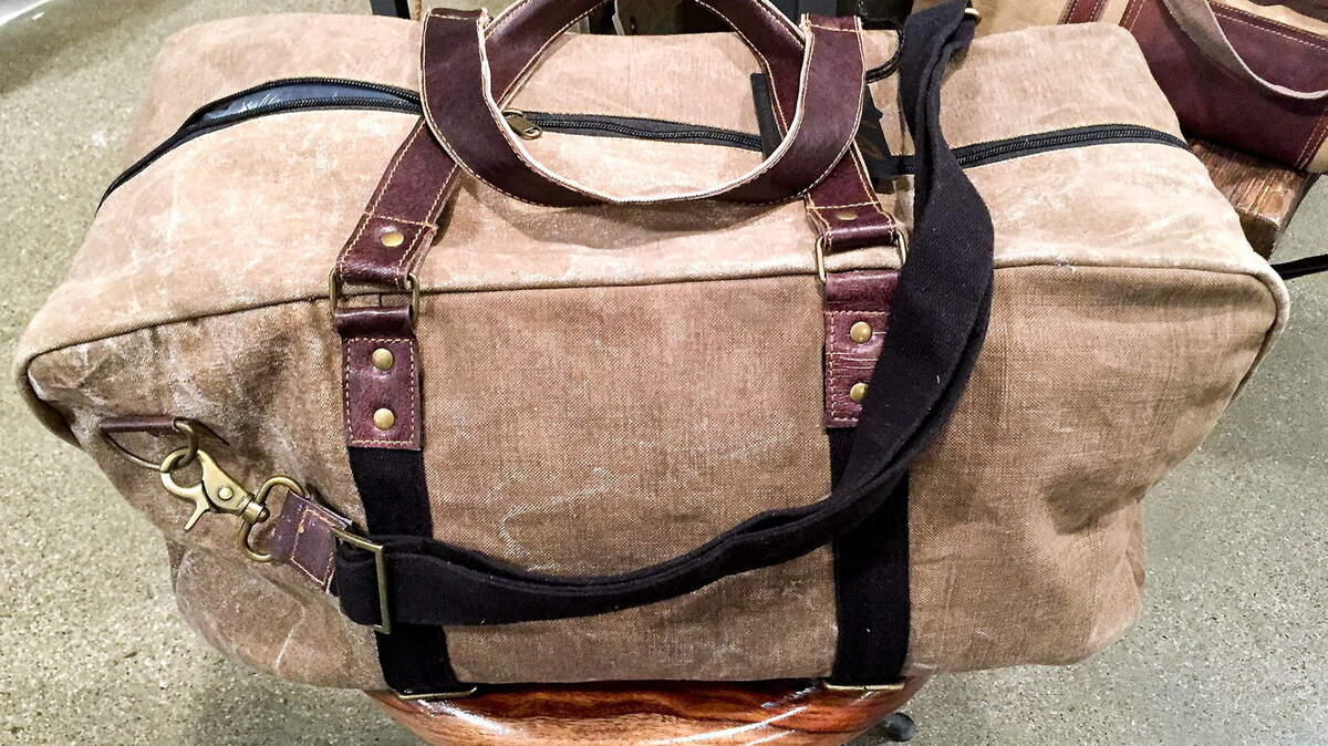 This is the Brad Weekender by Mona B. It is made of leather and up-cycled army tents weathered by jungles, deserts, sun and rain.