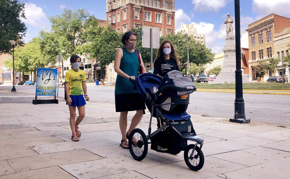 Elizabeth Harper pushes a baby stroller along Second Street in downtown Macon with her children, Charity, left, and Lillian. Baby Isaac is in the stroller. Elizabeth Harper, who along with her daughters wore masks amid the coronavirus threat, said, ”You’re wearing it to protect other people.”