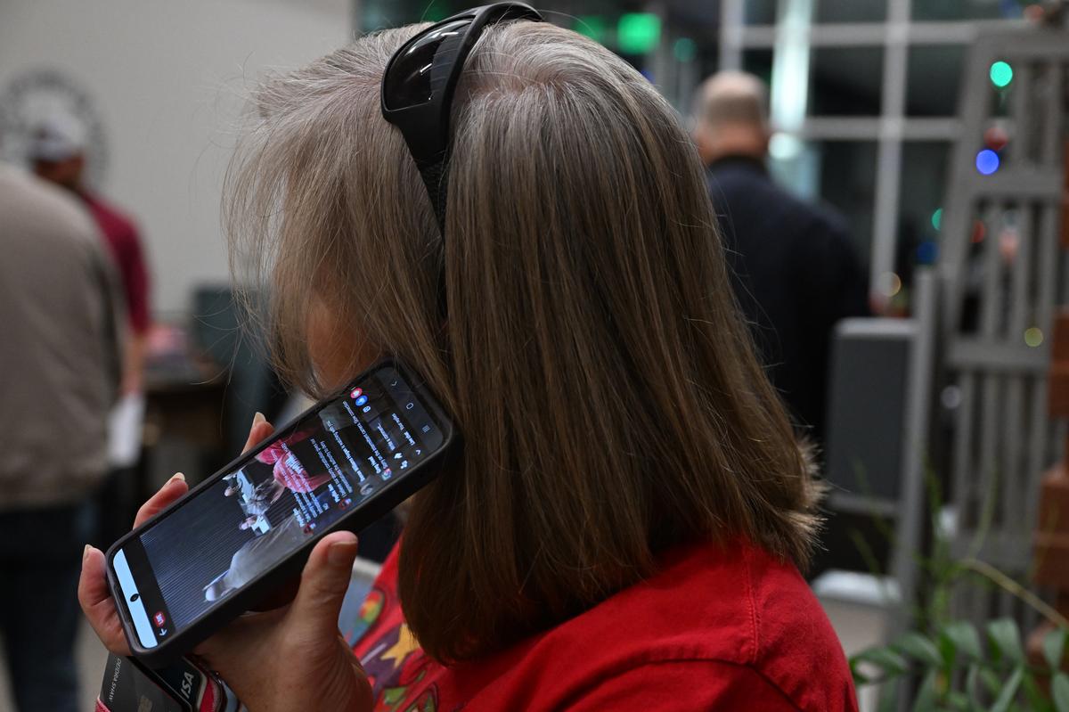 Deedee Shaw, who lives near Johnstonville Road, listens to a Facebook livestream from Greg Head who was inside the City of Forsyth Planning & Zoning meeting on Monday, Dec. 22, 2025, at Forsyth City Hall in Forsyth, Georgia. Dozens of people aiming to attend a Forsyth Planning & Zoning meeting gathered in the lobby outside after the meeting room reached capacity. 