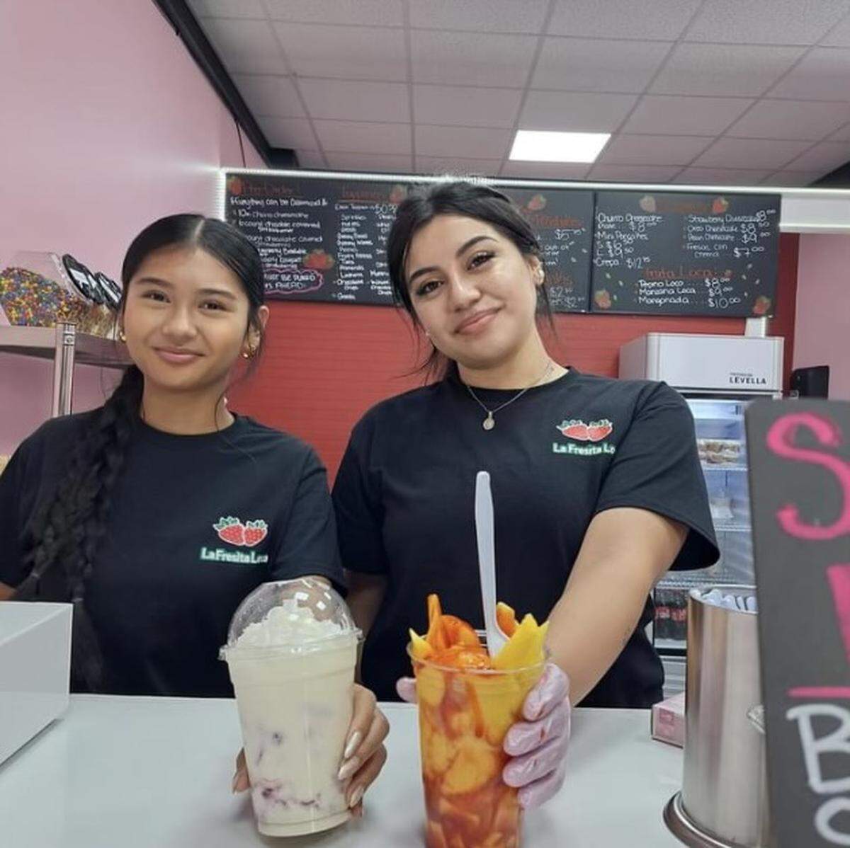 Shania Bautista, left, serves up a Fresas Con Crema, and Jessica Olivera holds up a Mangonada at La Fresita Loca, a new dessert shop specializing in Hispanic desserts near Byron.
