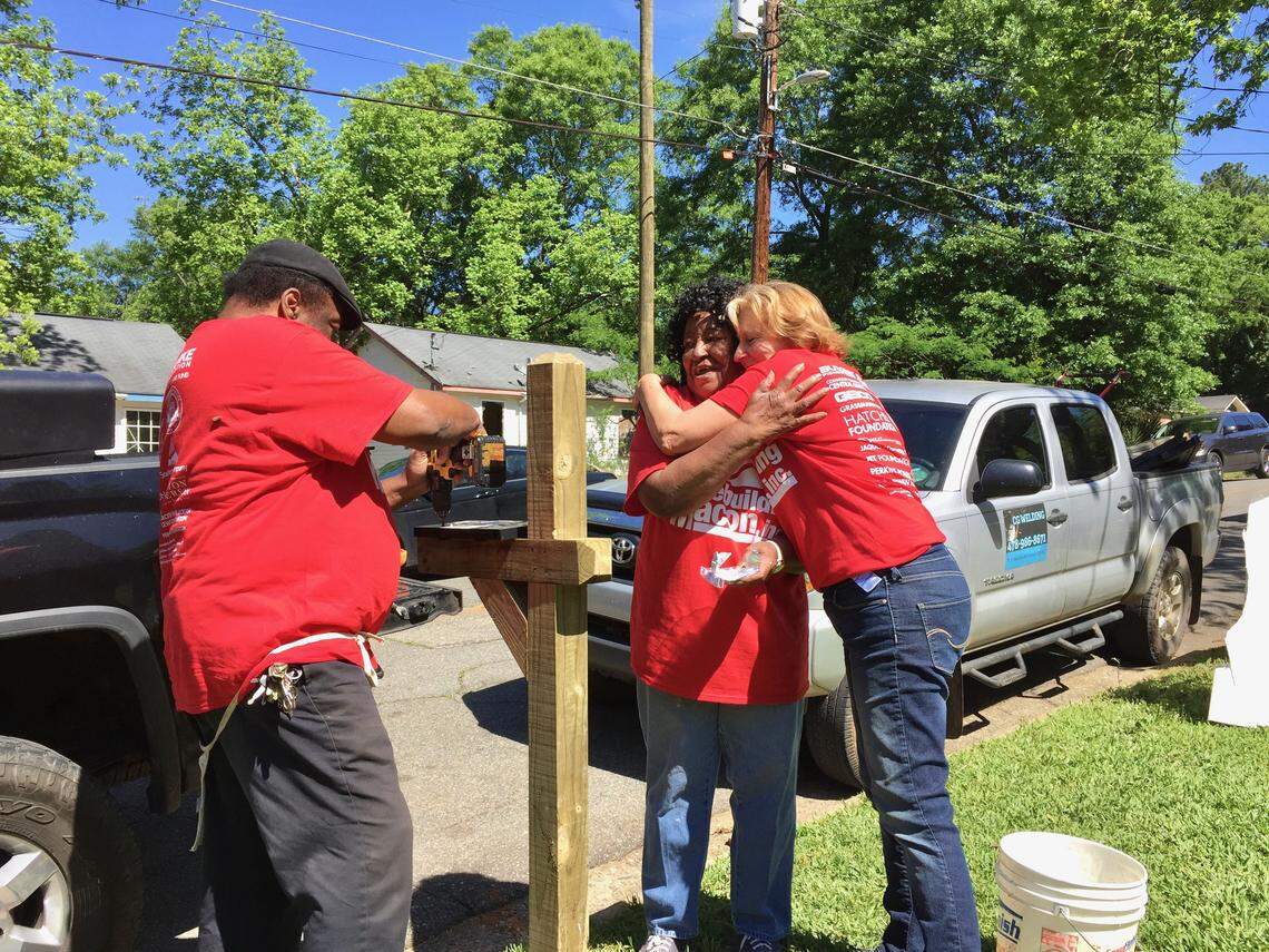 Executive Director of Rebuilding Macon Debra Collins, right, hugs long-time volunteer Melineaze Lowe, center, while she and another volunteer building a mailbox during the organization’s annual Macon Rebuilding Day April 27, 2019.