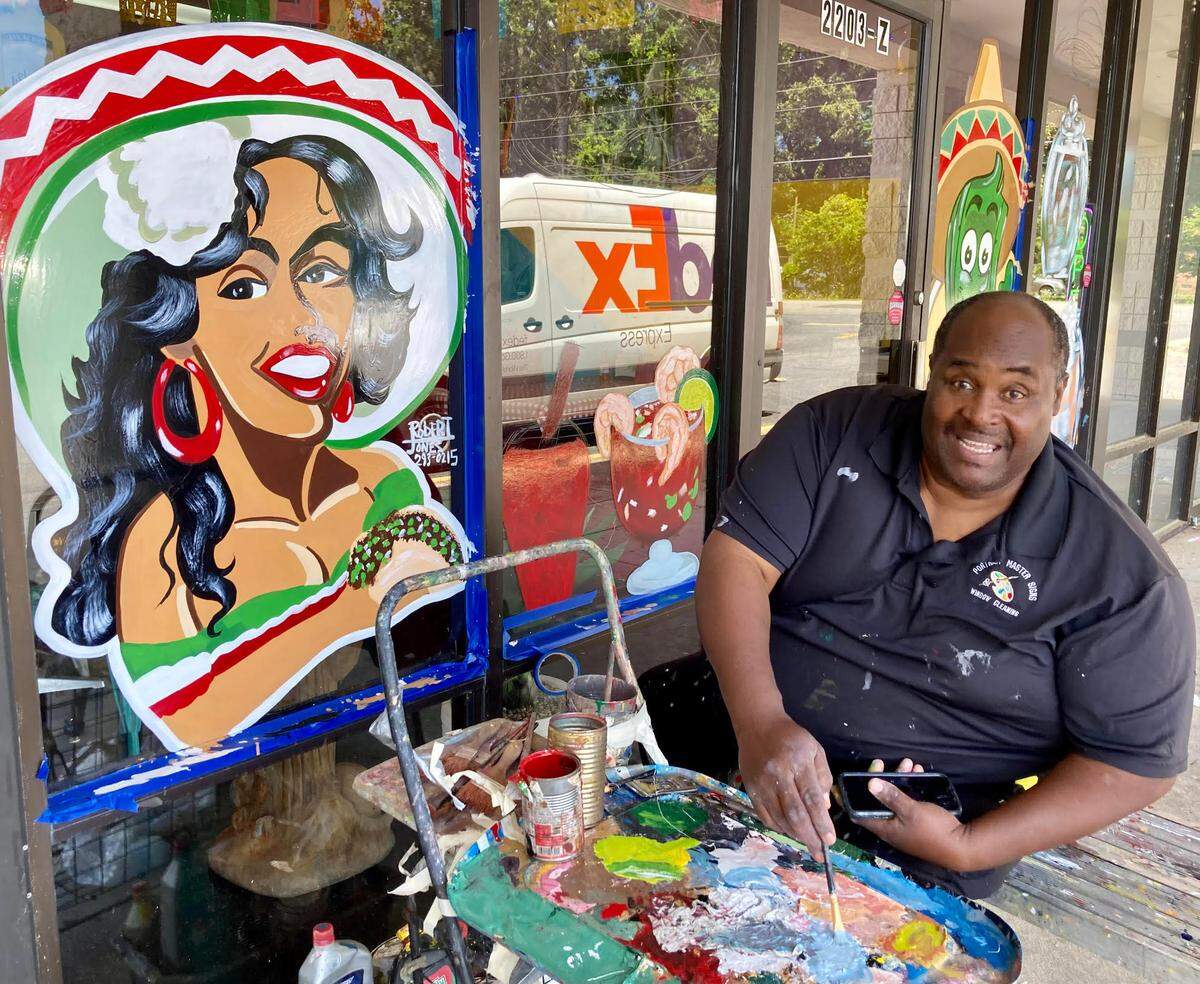 Middle Georgia artist Robert Jones paints a window at Taqueria la Pina Loka in Warner Robins.