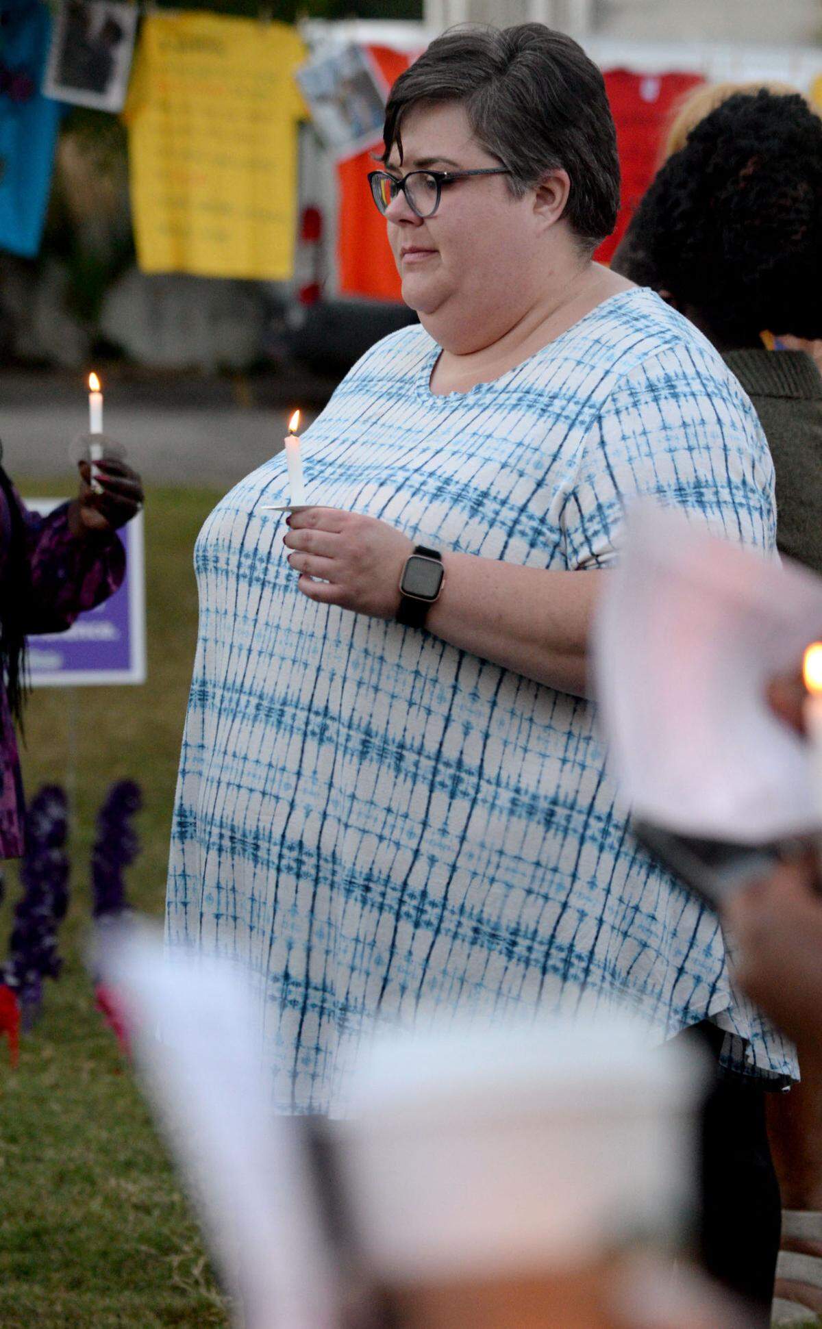 Emily Smallwood, the women’s division administrative assistant for the Rescue Mission of Middle Georgia, bows her head in prayer at a candlelight vigil for Domestic Violence Awareness Month in Rosa Parks Square.