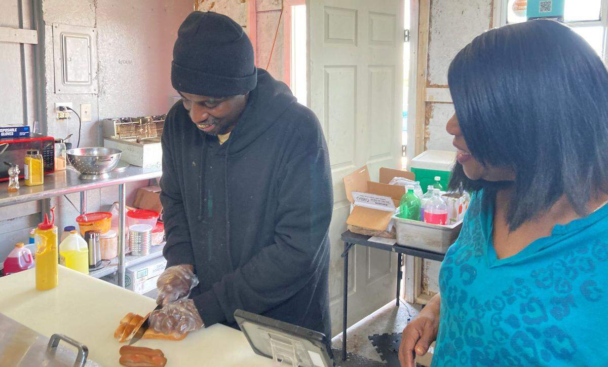 Tony Walker, owner of Doggie Dogs on Pio Nono Avenue in Macon, slices up a couple of hot dog buns to make a scrambled dog. A scrambled dog is two hot dogs cut up and topped with chili, nacho cheese, barbecue chicken, shredded chicken and pickles. His mom, Helen Walker Law, looks on.