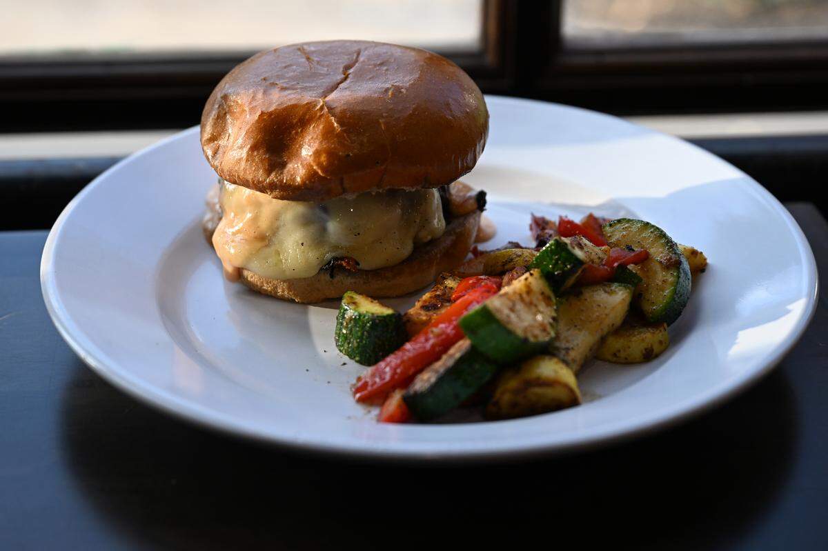 The Stuffed Kilpatrick served with a side of seasonal vegetables from Bearfoot Tavern. The burger features a beef patty stuffed with corned beef and Swiss cheese, topped with sauerkraut. 
