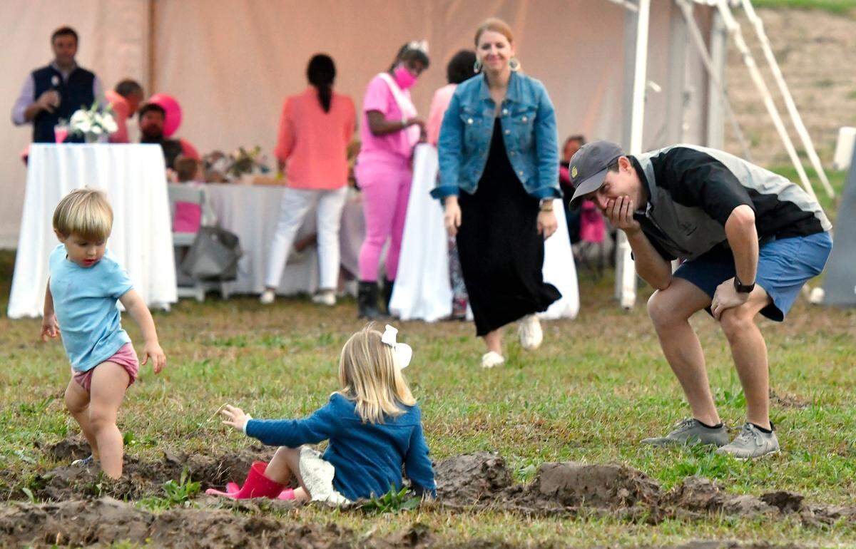 Will Kilpatrick reacts as Caroline Coker, 4, fall in the mud while playing with his son Guy, 2, during the Cherry Blossom Festival Tunes and Balloons finale Sunday night at Middle Georgia State.