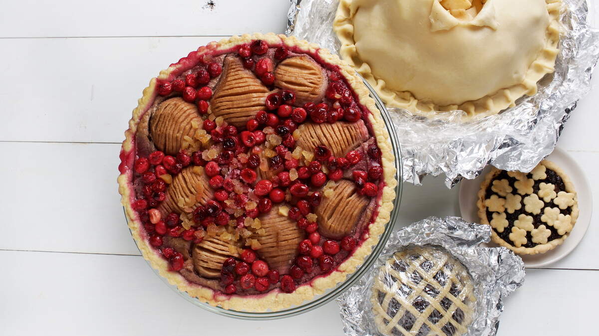 A few cooked and uncooked pies, clockwise from top, are Zesty Apple Pie, Boozy Dried-Fruit Pie, Pecangipane Pear and Cranberry Tart.