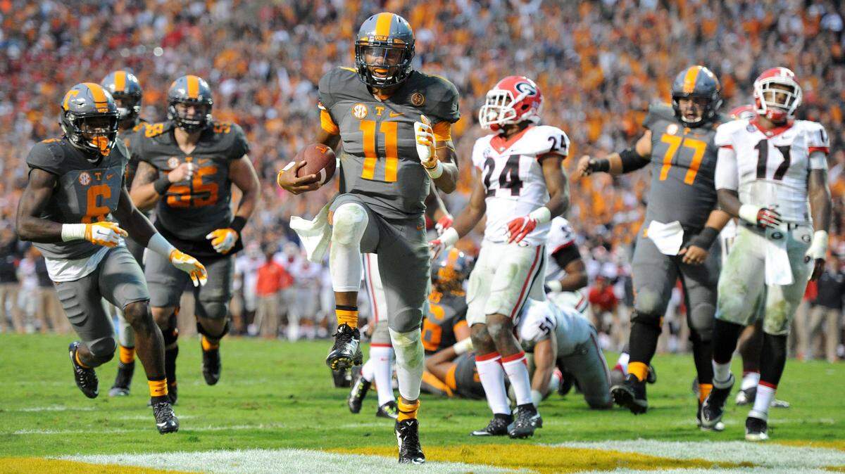 Tennessee quarterback Joshua Dobbs (11) beats a tackle by Georgia strong safety Dominick Sanders (24) to give Tennessee a 38-31 lead during the second half of an NCAA college football game, in Knoxville, Tenn. on Saturday, Oct. 10, 2015. (Adam Lau/Knoxville News Sentinel via AP) MANDATORY CREDIT