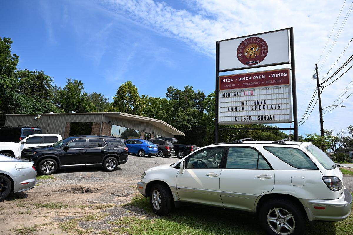 Vehicles park outside of Home Slice Pizza during lunch on Tuesday, Aug. 26, 2025, in downtown Perry, Georgia. The pizza restaurant opened in July and offers brick oven pizza, wings and more with lunch and family specials.