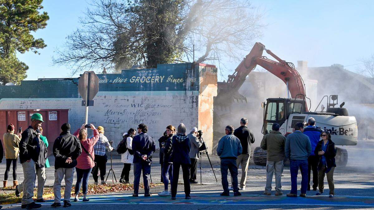 Macon-Bibb County officials and Vineville neighborhood residents watch Wednesday morning as an excavator tears down the former Bateman and Wade Grocery at 2283 Clayton St.