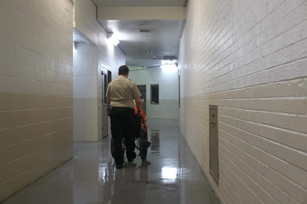 A Floyd County Sheriff’s Office deputy pushes the wheelchair of a CorrectHealth patient back to his cell.